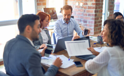 Group,Of,Business,Workers,Working,Together.,Sitting,On,Desk,Using