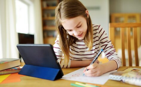 Preteen,Schoolgirl,Doing,Her,Homework,With,Digital,Tablet,At,Home.